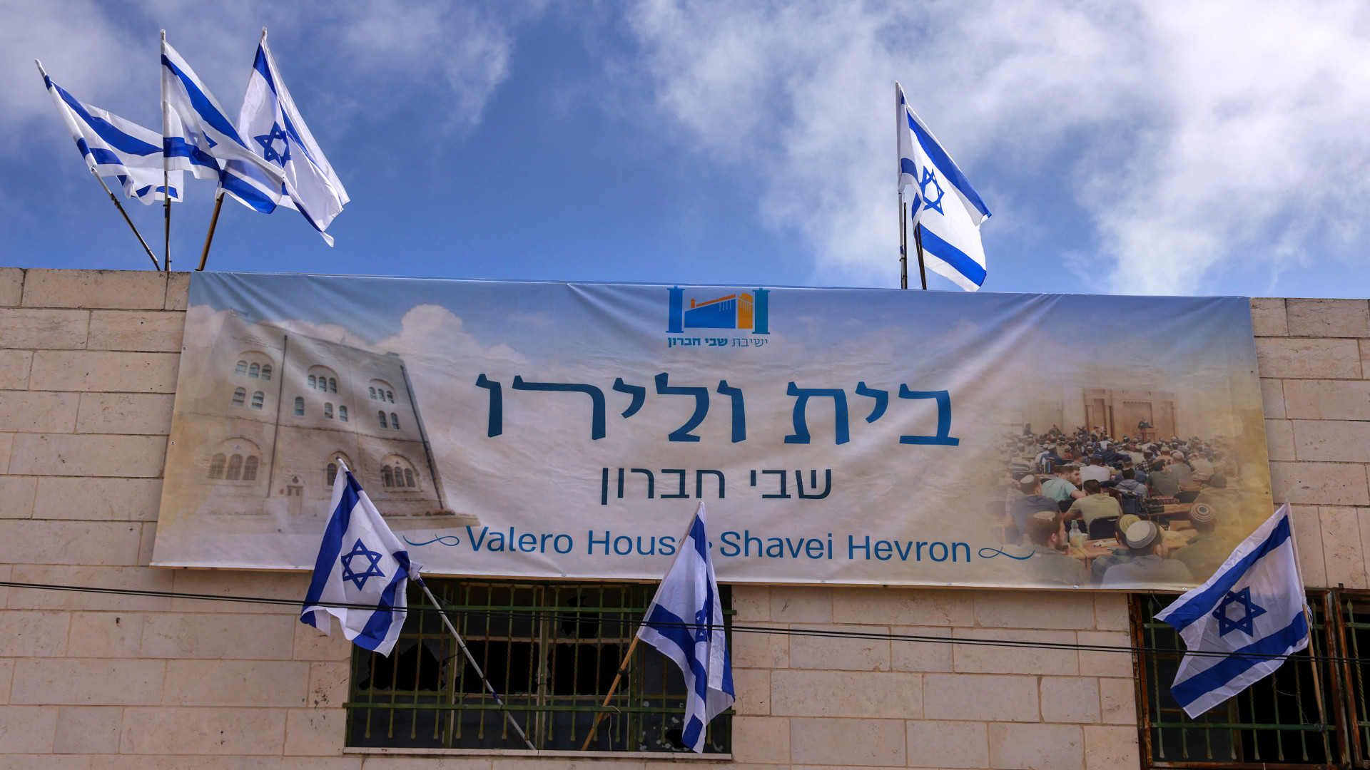 Israeli flags hang from a house at the entrance to the Palestinian market in Hebron’s old city, seized the previous night by Israeli settlers, on 3 September 2025 in the occupied West Bank (Hazem Bader/AFP)