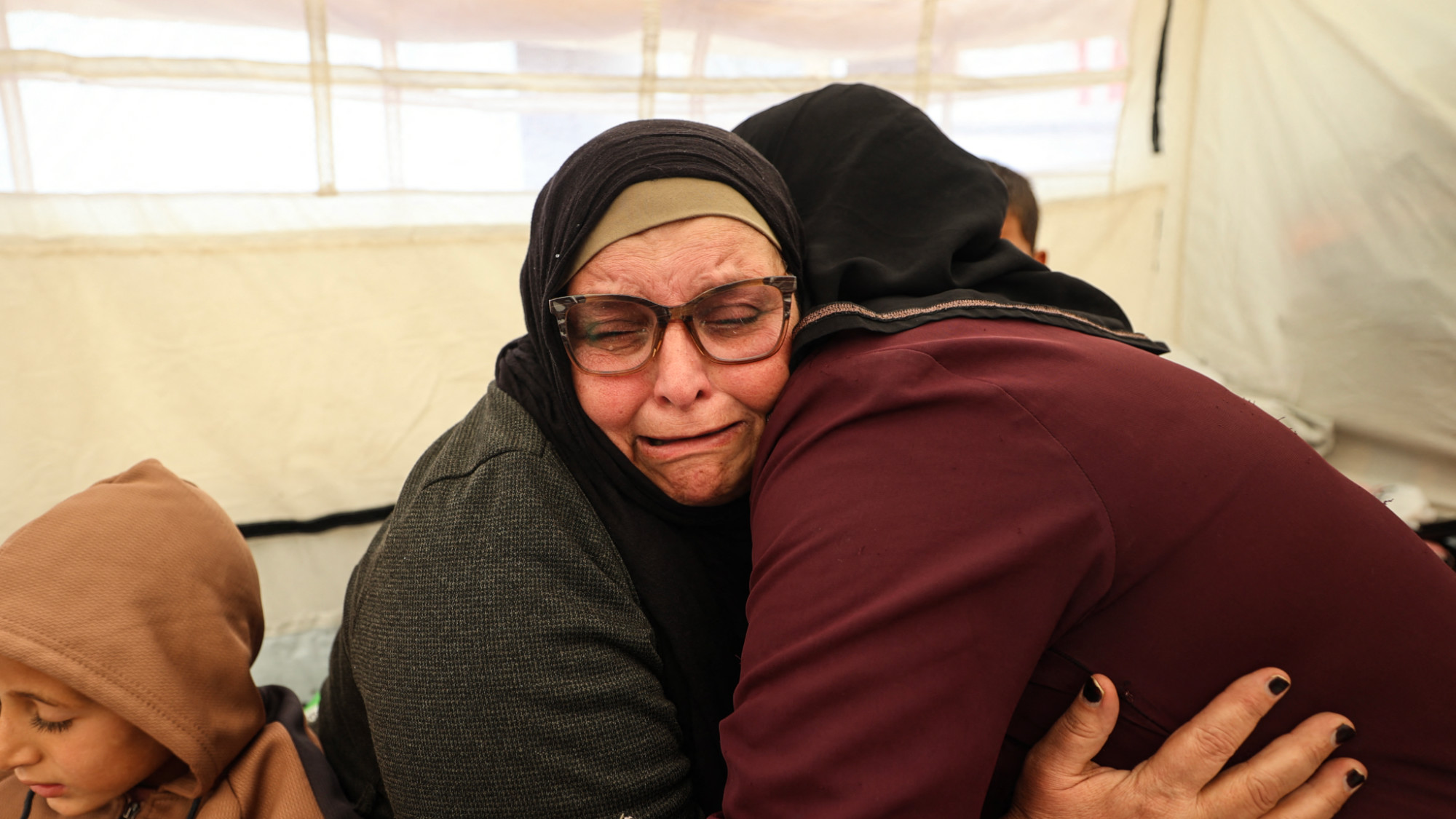 Huda Abu Abed reacts while sitting with her loved ones inside a  tent in Khan Younis, in the southern Gaza Strip, on 3 February 2026, after returning from Egypt via the Rafah crossing (AFP/Eyad Baba)