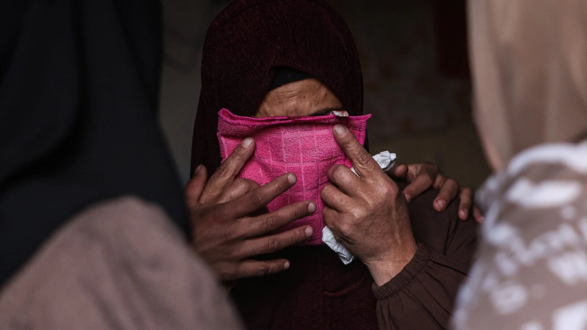 A female relative covers her face with a small hand towel stained with the blood of a relative killed in an Israeli strike, during a funeral in Khan Yunis in the southern Gaza Strip on 27 February 2026 (Bashar Taleb/AFP)