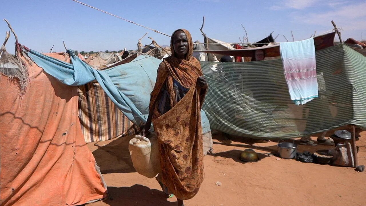 Awadeya, a displaced woman from el-Fashir, carries water at a camp in Tawila, North Darfur, Sudan, after fleeing clashes involving the Rapid Support Forces, 15 November 2025 (Reuters/Mohamed Jamal)