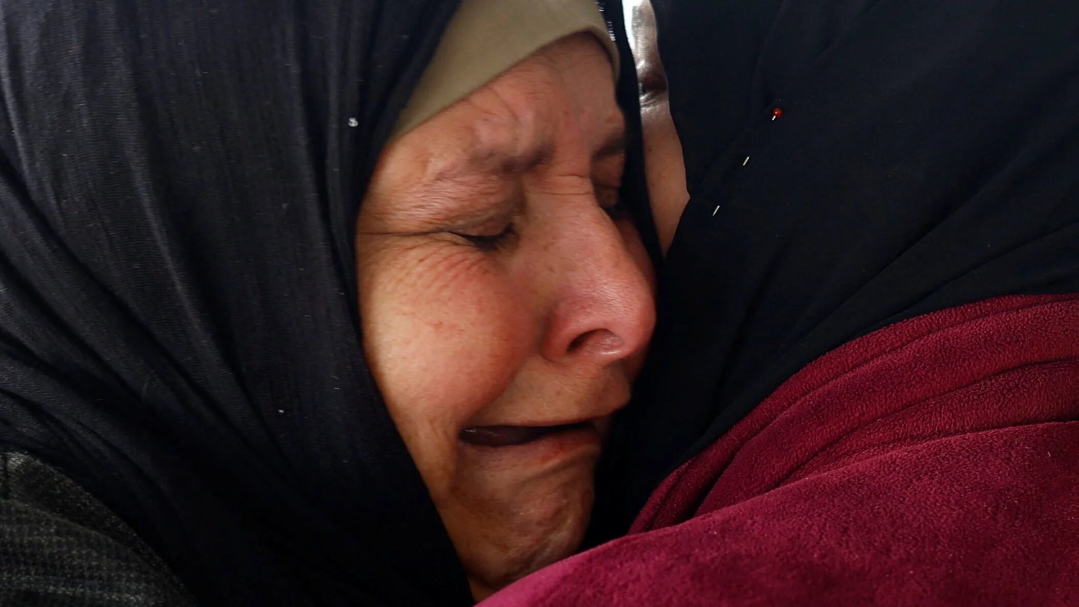 Huda Abu Abed, 57, cries as she is embraced by her sister inside a tent after returning to Gaza through the Rafah crossing, in Khan Younis on 3 February 2026 (Reuters/Mahmoud Issa)