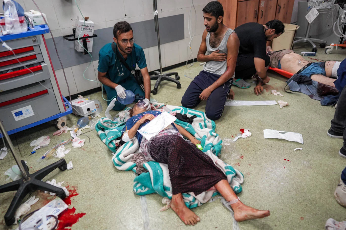 A medic helps an injured woman breathe through an oxygen mask while lying on the floor at a trauma ward at Nasser Medical Complex in Khan Yunis, Gaza, in July 2024 (AFP)