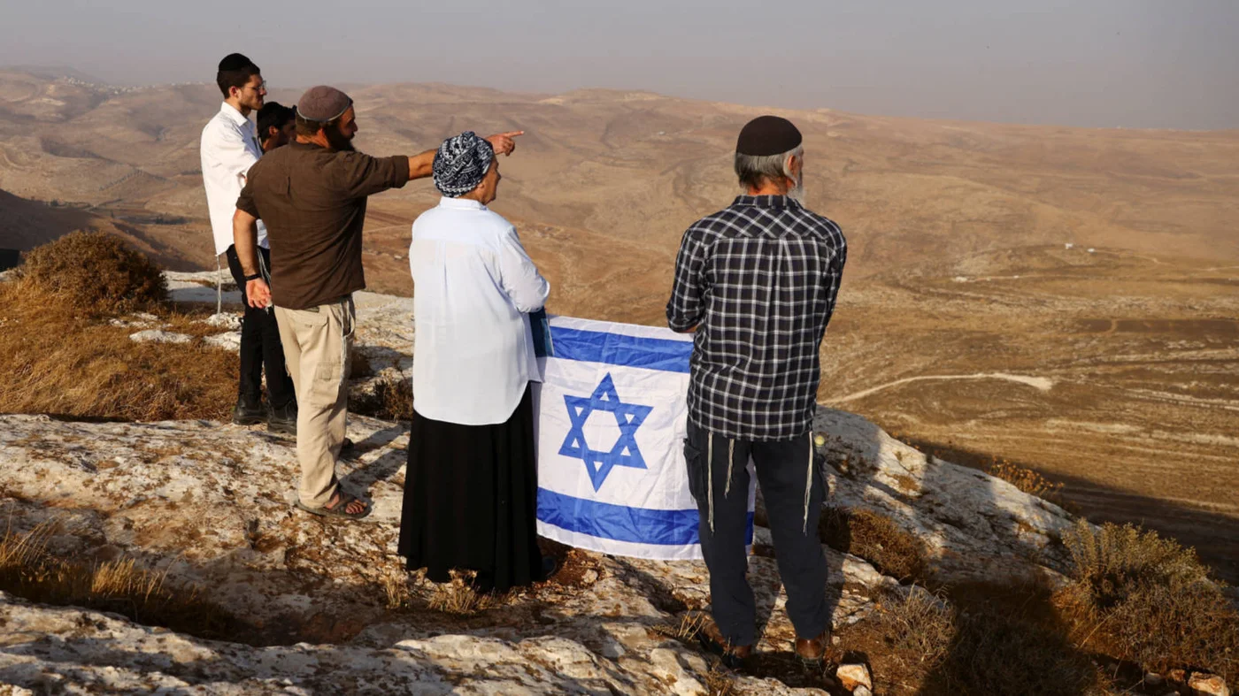 Daniella Weiss holds an Israeli flag during a scouting mission to find hilltops to settle near the Israeli settlement of Kokhav Hashahar, Israeli-occupied West Bank, in November 2022 (Reuters) 