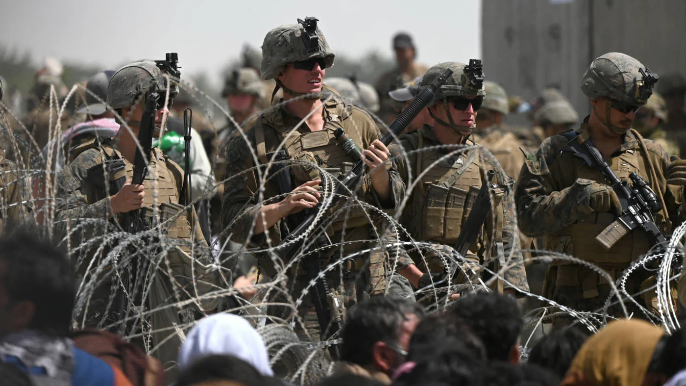 US soldiers stand guard behind barbed wire near Kabul airport as Afghans try to flee the country on 20 August 2021 (AFP)